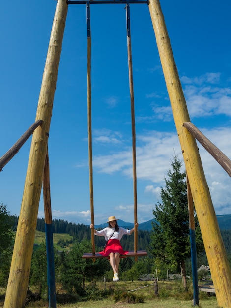Foto vrouw reiziger genieten van swingen op hemelse schommel en uitzicht op de bergen
