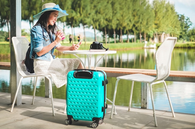 vrouw reiziger hebben een bagage zittend op de stoel en het nemen van foto-view van de natuur