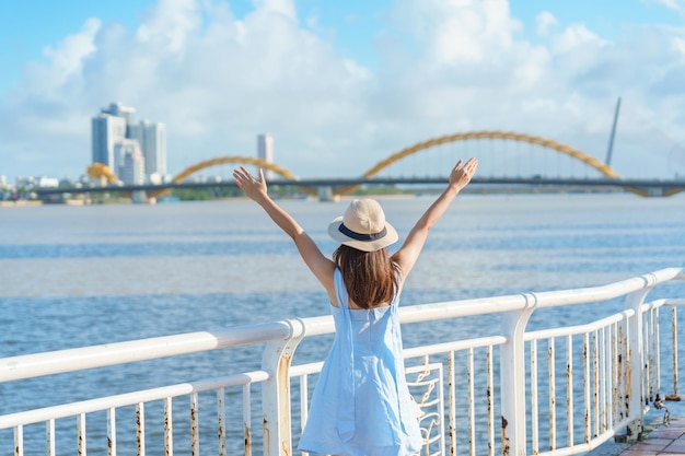 Vrouw Reiziger met blauwe jurk op bezoek in de stad Da Nang Toerist die het uitzicht op de rivier bezichtigt met Dragon Bridge Landmark en populair voor toeristische attractie Vietnam en Zuidoost-Azië reisconcept