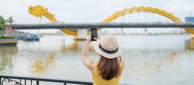 Vrouw Reiziger met gele jurk op bezoek in Da Nang Toerist die het uitzicht op de rivier bezichtigt met Dragon bridge bij love lock bridge Landmark en populair Vietnam en Zuidoost-Azië reisconcept