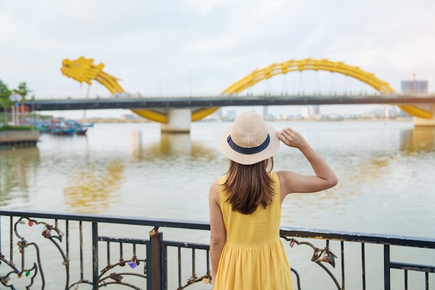 Vrouw Reiziger met gele jurk op bezoek in Da Nang Toerist die het uitzicht op de rivier bezichtigt met Dragon bridge bij love lock bridge Landmark en populair Vietnam en Zuidoost-Azië reisconcept