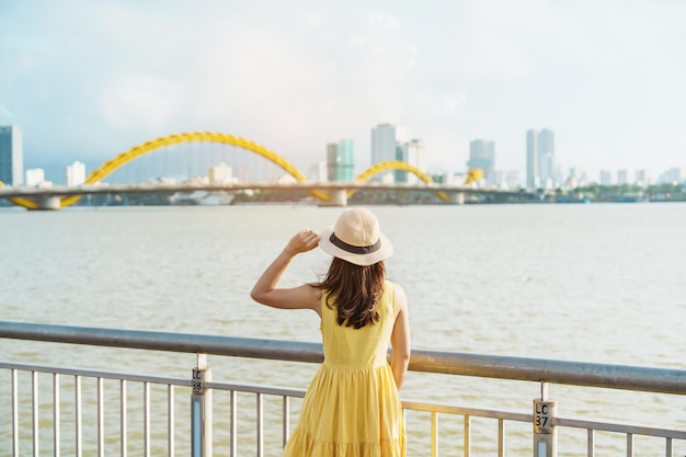 Vrouw Reiziger met gele jurk op bezoek in de stad Da Nang Toerist die het uitzicht op de rivier bezichtigt met Dragon Bridge Landmark en populair voor toeristische attractie Vietnam en Zuidoost-Azië reisconcept