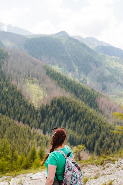 Vrouw reiziger met rugzak kijken naar verbazingwekkende bergen en bos, reislust reizen concept, ruimte voor tekst