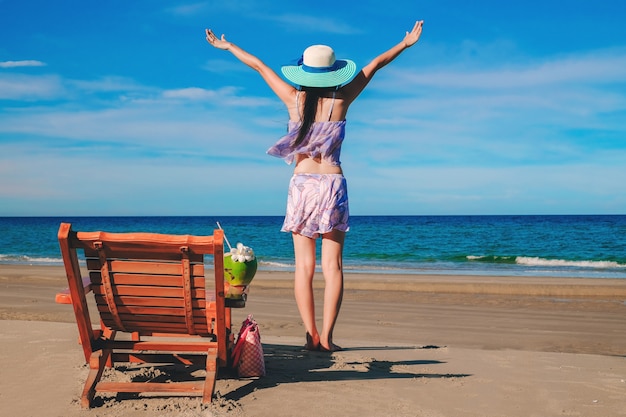 vrouw reiziger permanent en blij op het strand tijdens haar vakantie