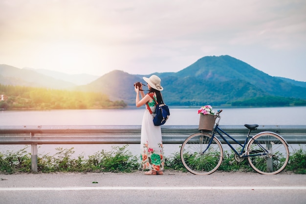 vrouw reiziger permanent naast fiets en nemen foto van het meer