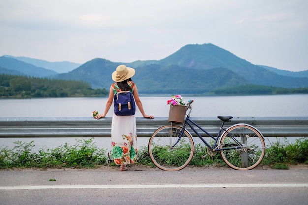 vrouw reiziger permanent naast fiets in de buurt van het meer achtergrond is berg op vakantie.