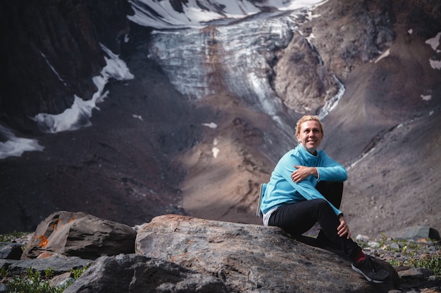 Vrouw reiziger zittend op een rots hoog in de bergen
