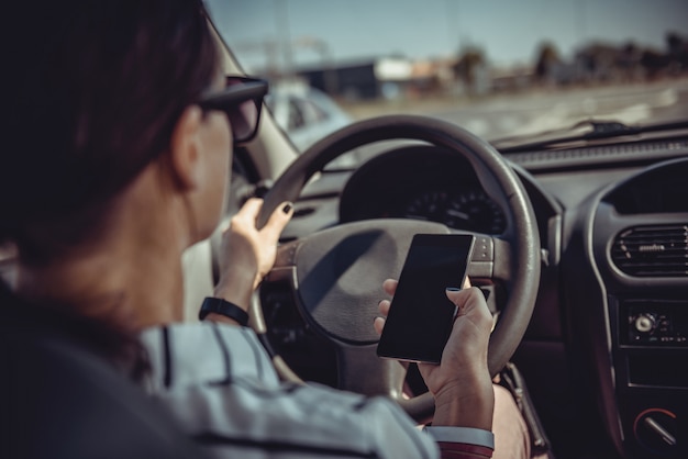 Vrouw rijdende auto en het gebruik van slimme telefoon