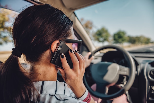 Vrouw rijdende auto en praten over slimme telefoon