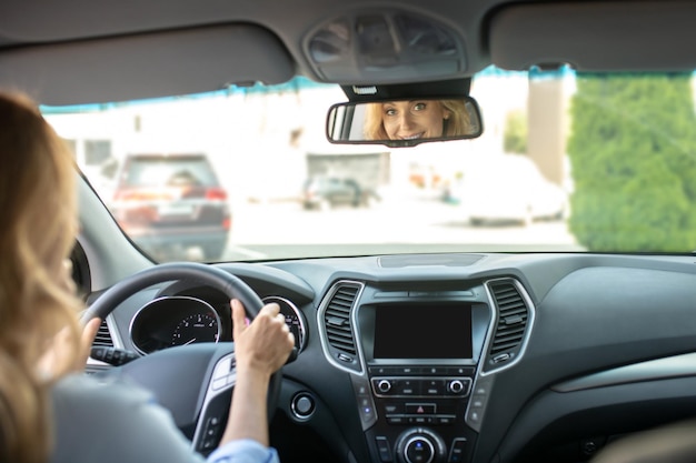 Vrouw rijdende auto kijken in achteruitkijkspiegel