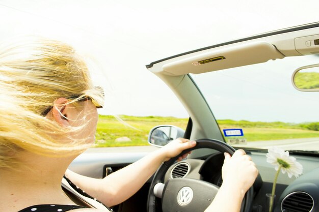 Foto vrouw rijdt een auto tegen een heldere lucht.