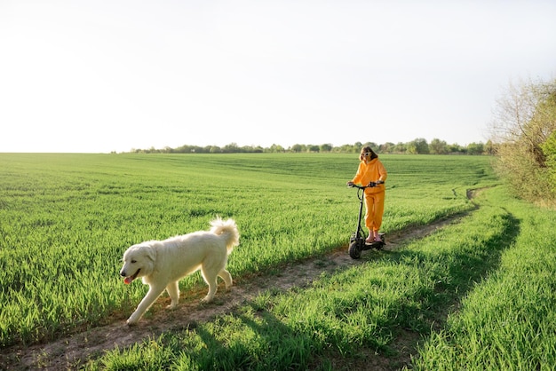 Vrouw rijdt elektrische scooter op groen veld met een hond