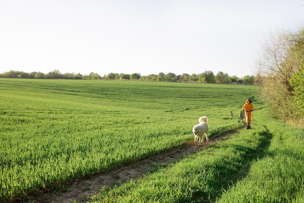 Vrouw rijdt elektrische scooter op groen veld met een hond