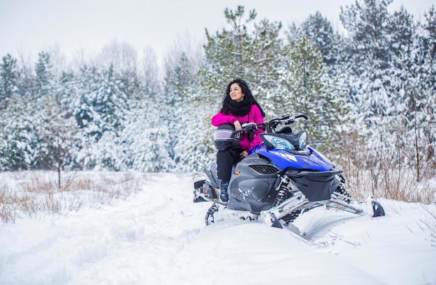 Vrouw rijdt sneeuwscooter in de bergen Meisje op een sport-sneeuwscooter in een bergbos Atleet rijdt op een sneeuwscooter in de bergen Sneeuwscooter in de sneeuw Concept wintersport