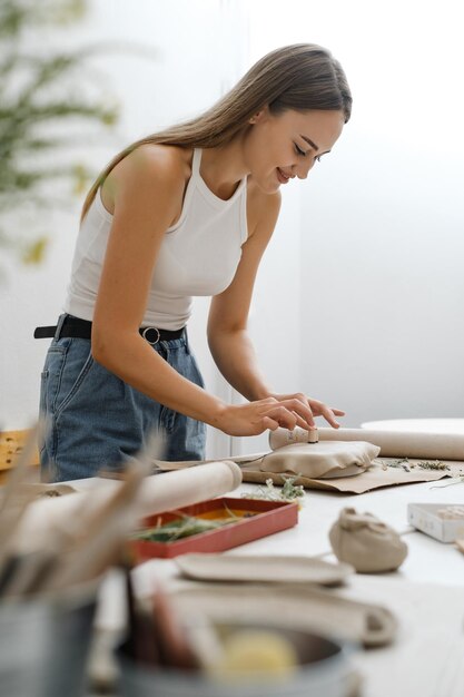 Vrouw rollende klei die keramische plaat maakt in studioworkshop