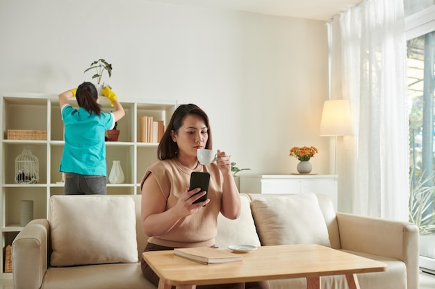 Vrouw rust als meid aan het schoonmaken is