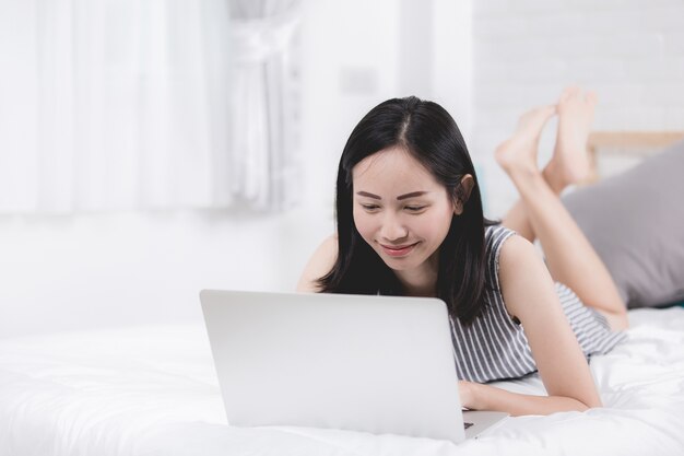 Vrouw rust en ontspannen op bed met behulp van laptopcomputer