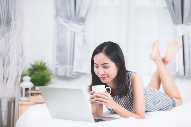 Vrouw rust en ontspannen op bed met behulp van laptopcomputer
