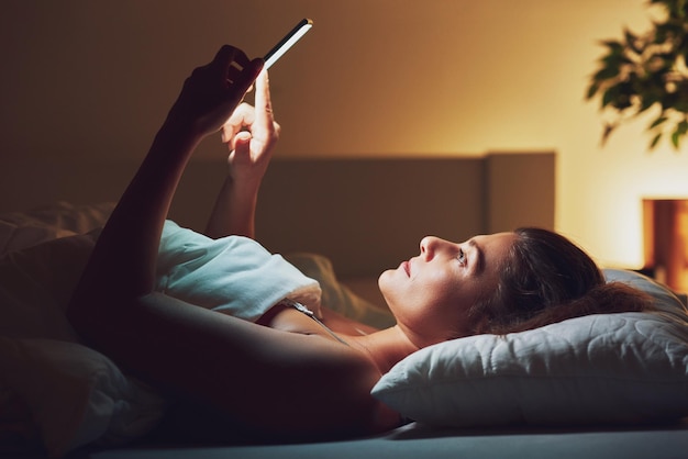 Vrouw 's nachts in bed met telefoon