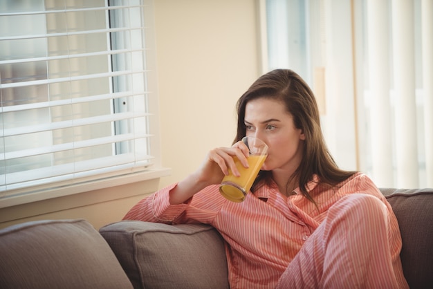 Vrouw sap drinken terwijl het kijken door raam