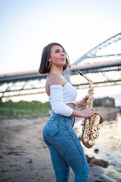 Vrouw saxofoon spelen bij zonsondergang