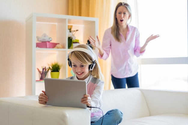 Vrouw scheldt haar tienerdochter uit, meisje luistert naar muziek in een koptelefoon en negeert haar moeder