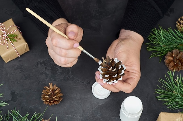 Vrouw schilderij dennenappels voor kerstversiering