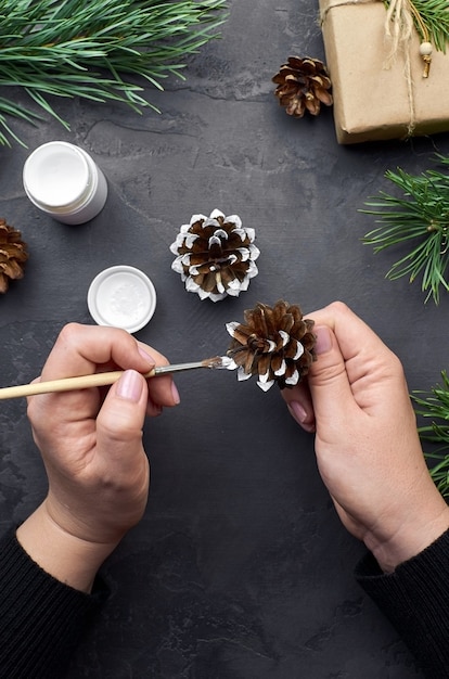 Vrouw schilderij dennenappels voor kerstversiering