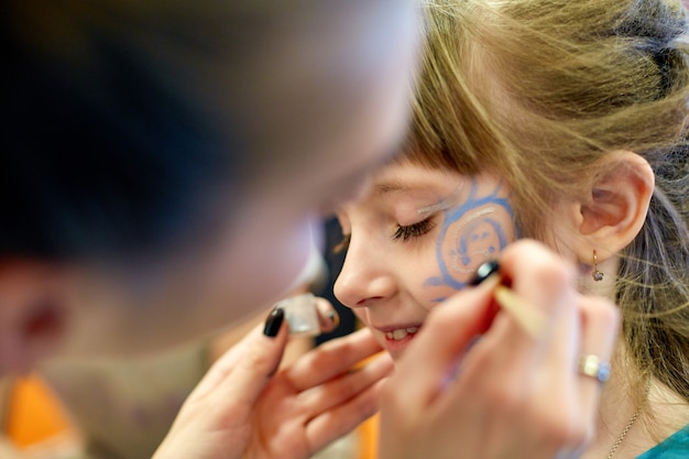 Vrouw schilderij gezicht van kind buitenshuis. baby schminken