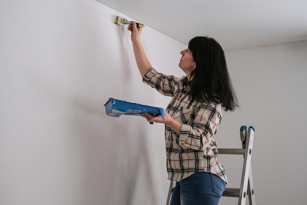 Vrouw schildert een muur met witte verf