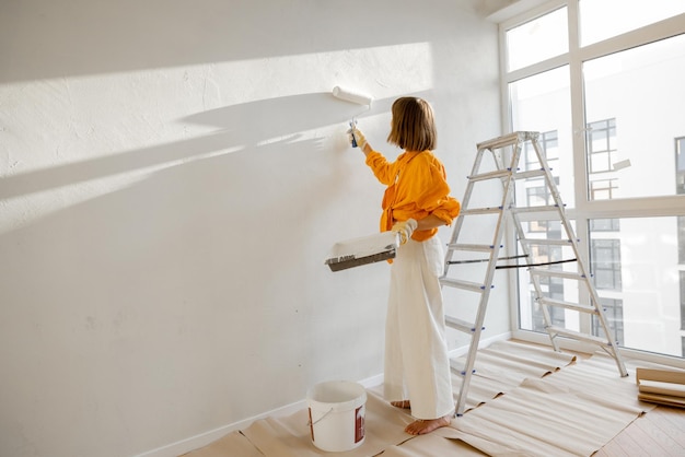 Vrouw schildert muur bij renovatie appartement