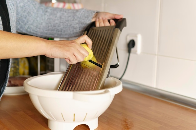 Vrouw schilt aardappelen met een dunschiller in haar keuken