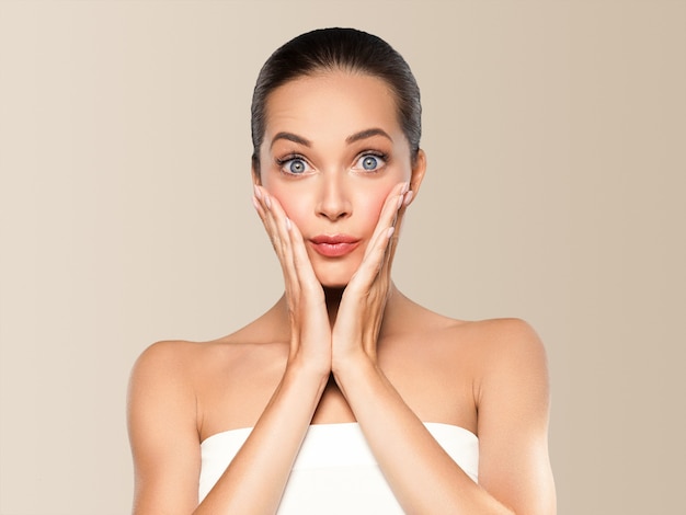 Vrouw schoonheid gezicht gezonde huid natuurlijke make-up mooie jonge model met handen. Op beige.