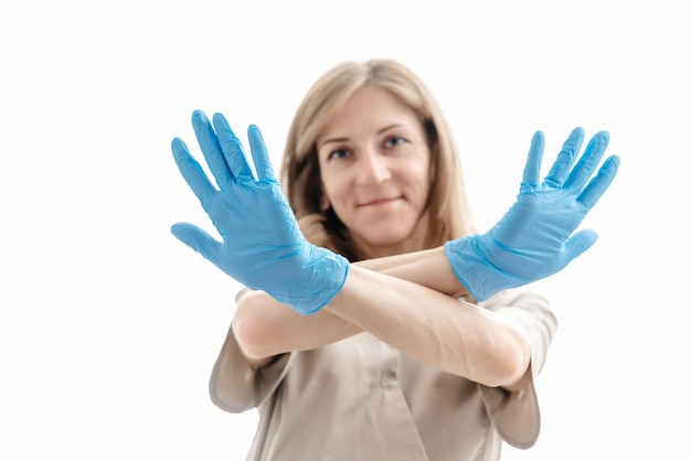 Vrouw schoonheidsspecialist in uniform en blauwe latex handschoenen met armen gekruist witte achtergrond concept van t