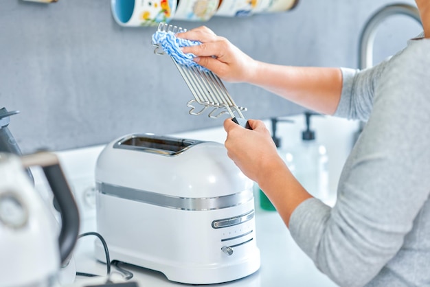 Vrouw schoonmaak grill of broodrooster machine in de keuken