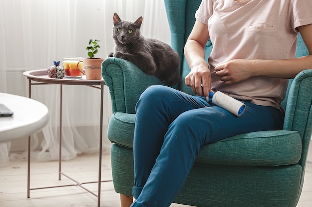 Vrouw schoonmaakkleren met kleverige roller van kattenhaar.