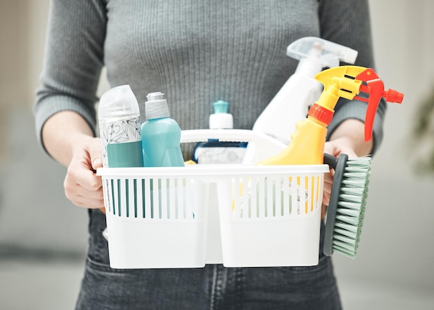 Vrouw schoonmaakster of huisvrouw met schoonmaakbenodigdheden wasmiddelen en hygiënehulpmiddelen of producten in een mand Handen van een huishoudster klaar om klusjes en huishoudelijk werk te doen voor een schoon en opgeruimd huis