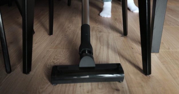 Foto vrouw schoonmaakt woonkamer met moderne witte stofzuiger uit het oogpunt van onder de tafel