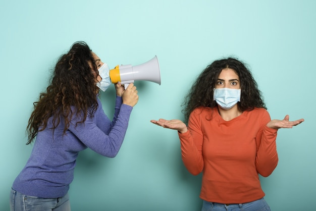 Vrouw schreeuwt met luidspreker naar een vriend, maar het is moeilijk te begrijpen met gezichtsmasker.