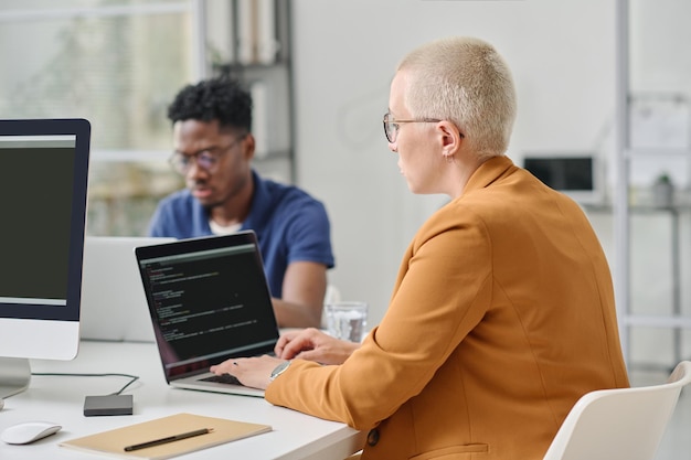 Vrouw schrijft codes op laptop op kantoor