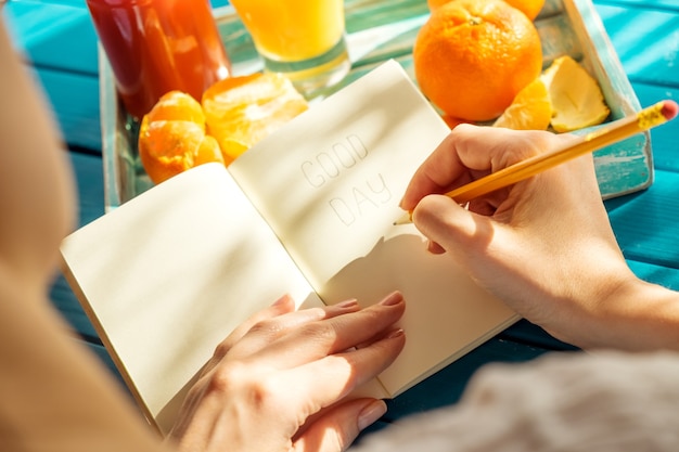 Vrouw schrijft in haar notitieboekje in de zonnige ochtend.