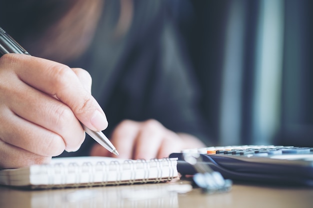 Vrouw schrijven en rekenmachine gebruiken