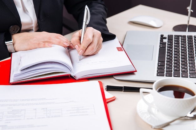 Vrouw schrijven in dagelijkse planner koffie en laptop