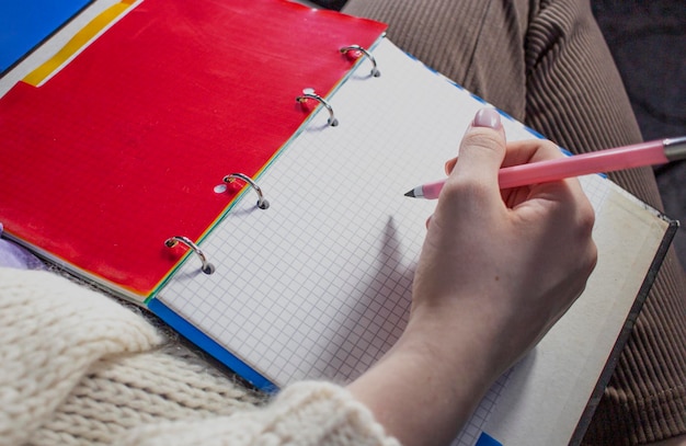 Vrouw schrijven in notebook met potlood huiswerk