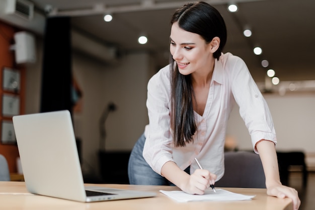 Vrouw schrijven info van laptop tot papierwerk