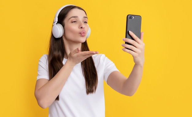 Vrouw selfie maken op smartphone luisteren naar muziek blow kiss influencer bloggen