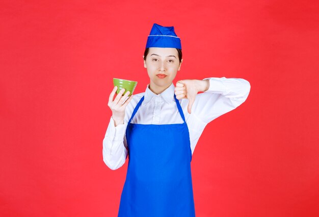 Vrouw serveerster in uniform met een groene kom en duim naar beneden.