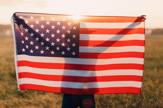 Vrouw silhouet op het gebied van landbouw buiten de vlag van de VS op zonsondergang
