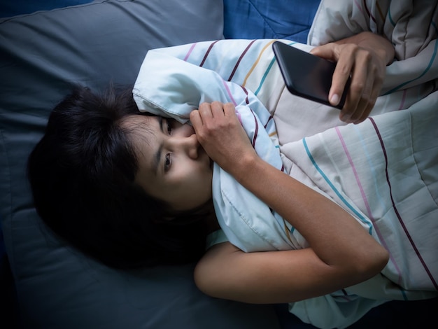 Vrouw slaapt en houdt 's nachts mobiel op het bed in de kamer