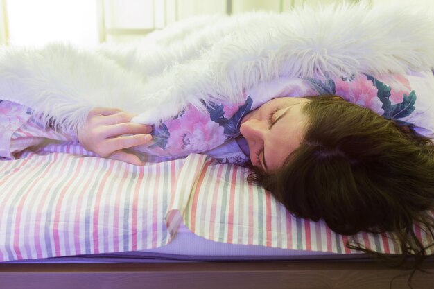 Vrouw slapen op het bed in de stralen van warm licht